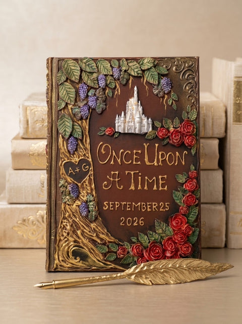 A decorative embossed journal styled like an antique fantasy book, featuring a castle motif, roses, grapes, and the text 'Once Upon a Time September 25 2026'. It is displayed upright on a tabletop with a gold feather pen in front and stacked books in the background.
