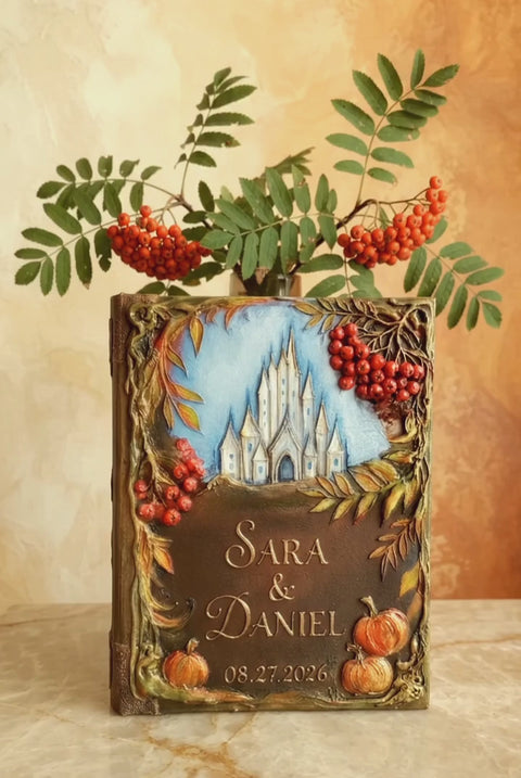 Personalized handmade hardcover Autumn wedding guest book  The cover features a painted blue sky with a 3D white castle, autumn leaves, red berries, and small pumpkins, with the names 'SARA & DANIEL' and the date