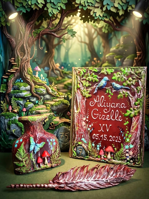 A personalized fantasy forest-themed keepsake set displayed on a tabletop, featuring a rectangular box with a red background, blue birds, mushrooms, and the names 'Aliana & Gizelle' with the date '05.15.