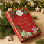 A red hardcover book styled as a Christmas gift with the title 'Santa's Naughty and Nice List 2027' on the cover, surrounded by pine branches, warm string lights, and holiday ornaments on a wooden surface.