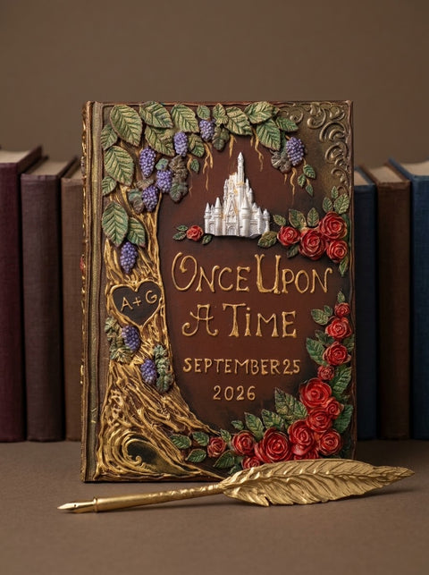 An ornate decorative journal standing upright on a tabletop, surrounded by vintage books in the background. The journal cover is dark brown with raised gold lettering reading 'Once Upon a Time September 25 2026,' a white castle motif near the top, red roses, green leaves, purple grapes, and a gold feather pen resting in front.