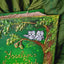 A close-up of a decorative book cover titled "Yoselyn's Enchanted Quince" featuring two gray owls perched on a tree branch with green leaves and brown trunk, set against a dark green embroidered fabric background.
