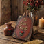 A rustic wooden sign with ornate gold lettering that reads 'Be Our Guest' and a small red rose, displayed on a wooden table with dried roses, a candle, and a gold feather quill in a styled setting.