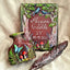 A personalized painted wooden keepsake box set displayed on a beige fabric background, featuring a rectangular box with a forest design, a matching small vase, and a decorative feather quill.