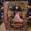 A custom, ornate hardcover wedding keepsake book standing upright on a wooden table. The book features intricate gold and brown baroque-style scrollwork borders, a central illustration of a bride and groom under a chandelier, and personalized gold text reading 'Kara & Bailey 03.
